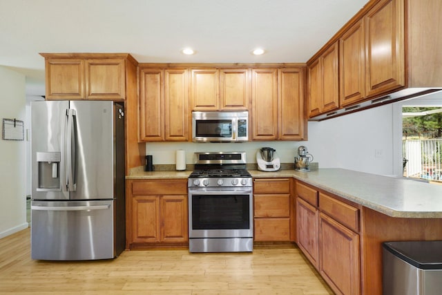 kitchen featuring stainless steel appliances, light wood-type flooring, and kitchen peninsula