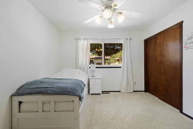 carpeted bedroom featuring ceiling fan and a closet