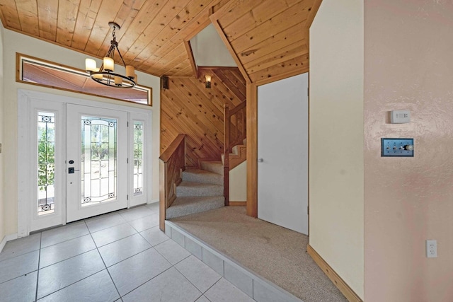 foyer featuring wood ceiling, wooden walls, light tile patterned floors, and an inviting chandelier