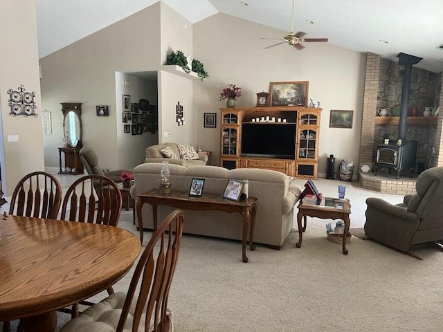 carpeted living room featuring high vaulted ceiling, ceiling fan, and a wood stove