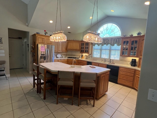 kitchen with dishwasher, stainless steel fridge, light tile patterned flooring, tile counters, and a center island with sink