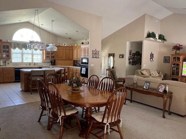 dining space featuring high vaulted ceiling, an inviting chandelier, light carpet, and sink