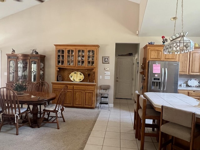 dining room with high vaulted ceiling and light tile patterned floors