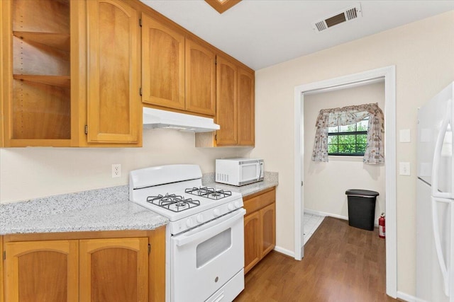 kitchen with dark hardwood / wood-style flooring, light stone counters, and white appliances