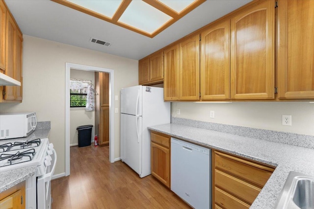 kitchen featuring light wood-type flooring, white appliances, and light stone countertops