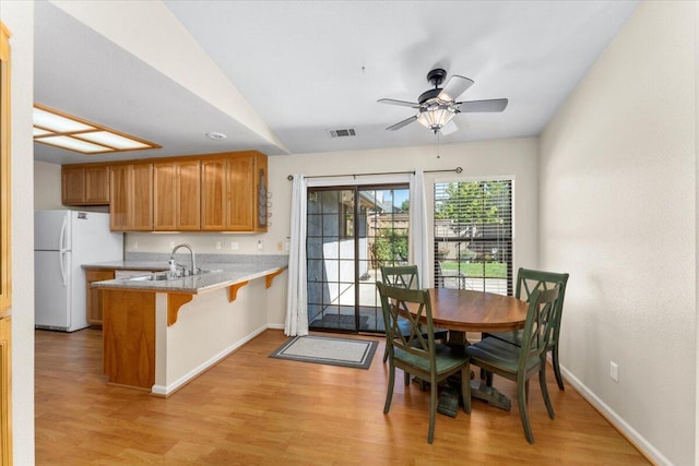 kitchen featuring a kitchen bar, kitchen peninsula, light hardwood / wood-style flooring, and sink