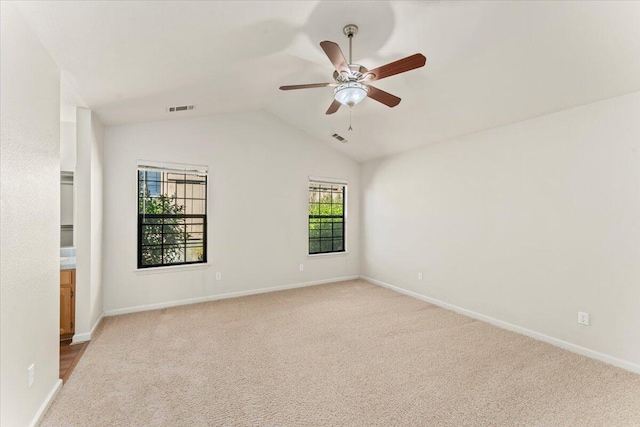 spare room with light colored carpet, ceiling fan, and vaulted ceiling