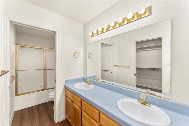 full bathroom featuring enclosed tub / shower combo, wood-type flooring, vanity, and toilet