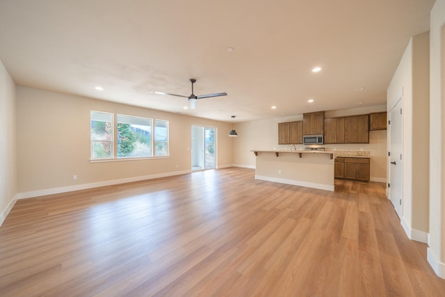 unfurnished living room with ceiling fan and light wood-type flooring