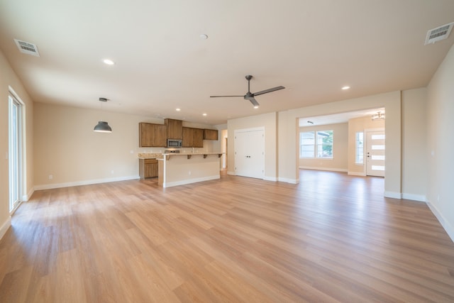 unfurnished living room featuring ceiling fan and light hardwood / wood-style flooring