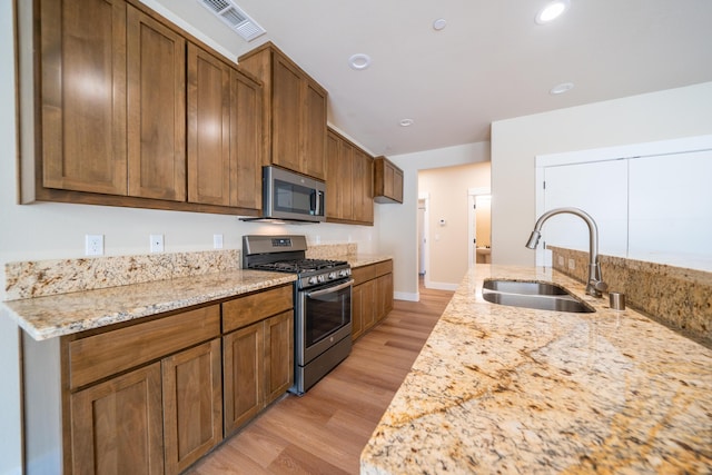 1132 Kellinger St, Redding, CA 96003 - kitchen with light stone countertops, light wood-style flooring, brown cabinets, stainless steel appliances, and a sink