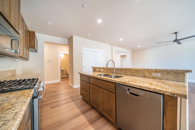 kitchen featuring light hardwood / wood-style floors, light stone counters, stainless steel appliances, ceiling fan, and sink