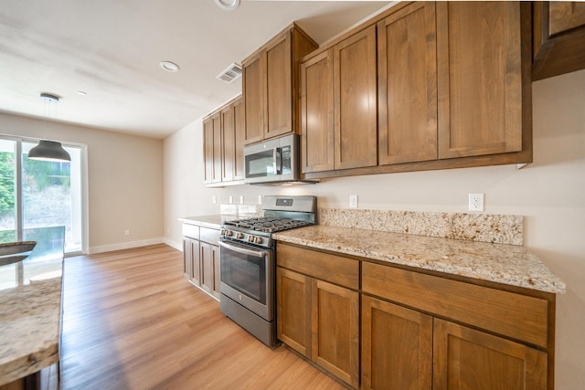 1132 Kellinger St, Redding, CA 96003 - kitchen featuring light wood-type flooring, visible vents, appliances with stainless steel finishes, and brown cabinets