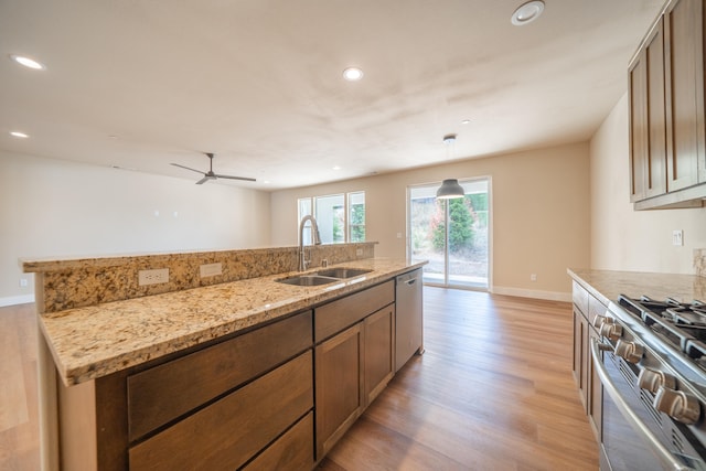 kitchen featuring light wood-type flooring, light stone counters, sink, appliances with stainless steel finishes, and ceiling fan