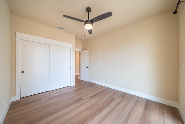 unfurnished bedroom with light hardwood / wood-style floors, ceiling fan, and a closet