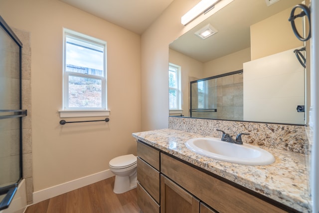 bathroom with hardwood / wood-style flooring, walk in shower, vanity, and toilet