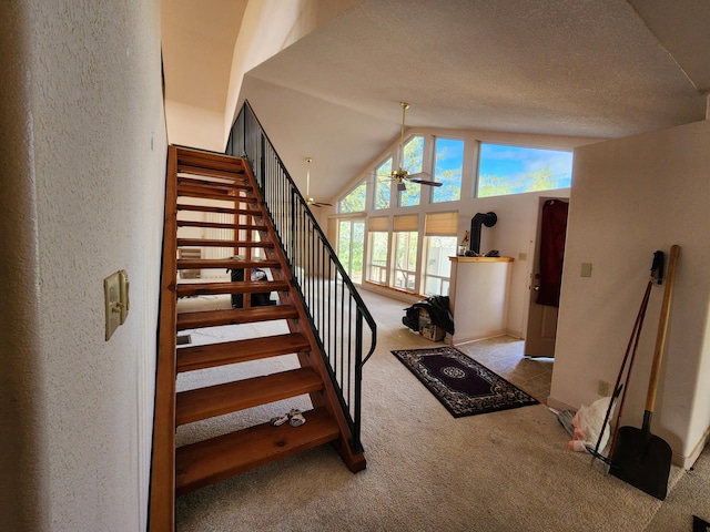 staircase with lofted ceiling, carpet, ceiling fan, and a textured ceiling