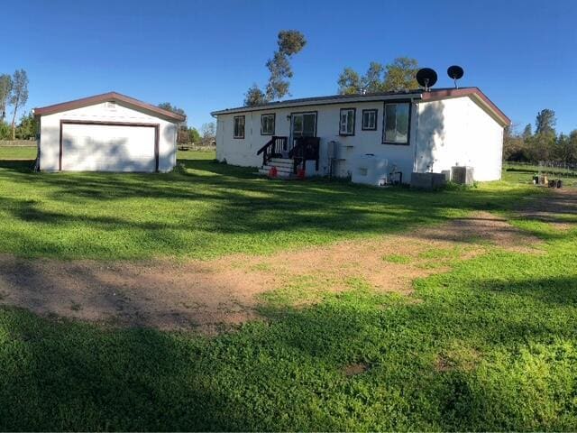 rear view of house with a garage, a yard, and central AC