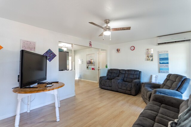 living room featuring ceiling fan, light wood-type flooring, and an AC wall unit