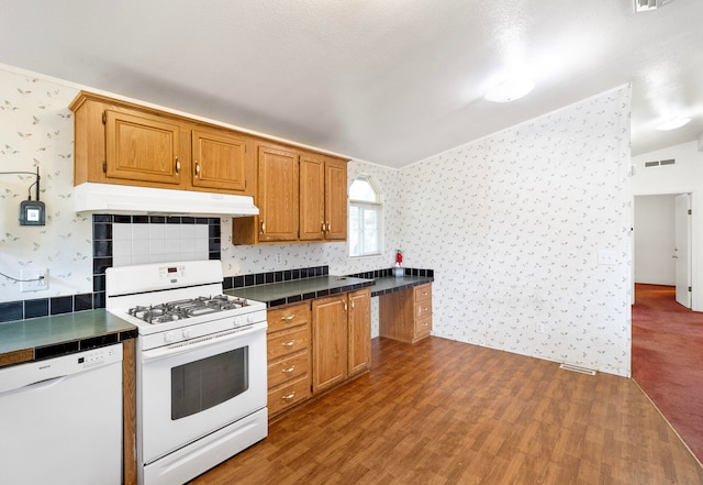 kitchen featuring white appliances, a textured ceiling, vaulted ceiling, and hardwood / wood-style flooring