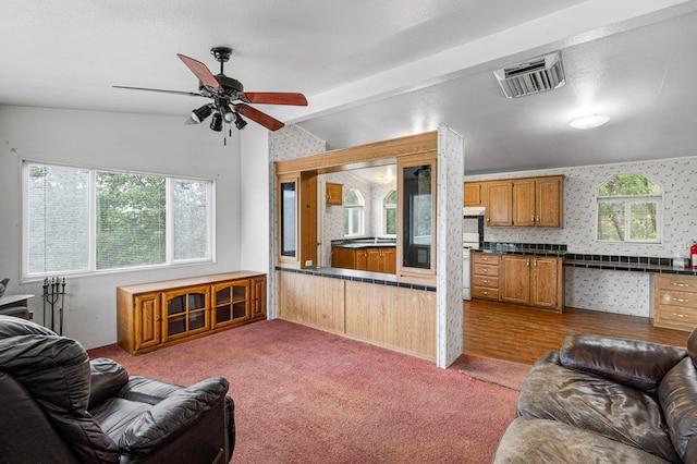 carpeted living room featuring vaulted ceiling with beams and ceiling fan