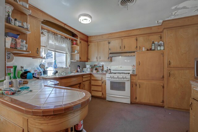 kitchen with tasteful backsplash, carpet floors, white range with gas cooktop, tile counters, and sink