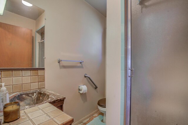 bathroom with walk in shower, toilet, and tasteful backsplash