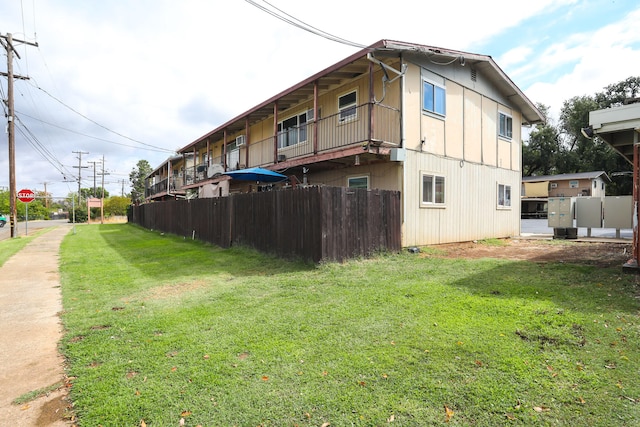 back of property featuring a balcony and a yard