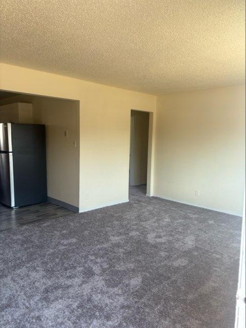 empty room featuring dark carpet and a textured ceiling