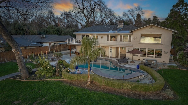 back house at dusk with a fenced in pool, a lawn, and a patio