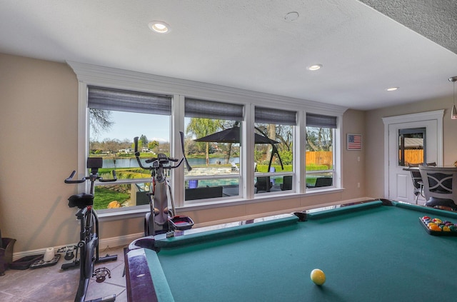 recreation room featuring pool table, a textured ceiling, a water view, and plenty of natural light