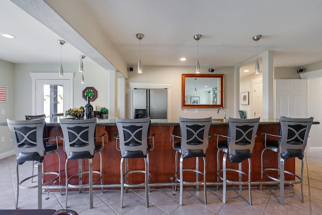 kitchen with hanging light fixtures, stainless steel fridge, and a kitchen bar