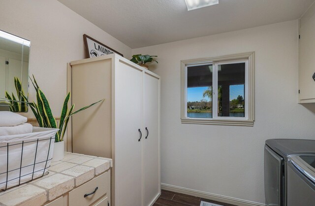 clothes washing area featuring cabinets, a textured ceiling, separate washer and dryer, and dark hardwood / wood-style flooring