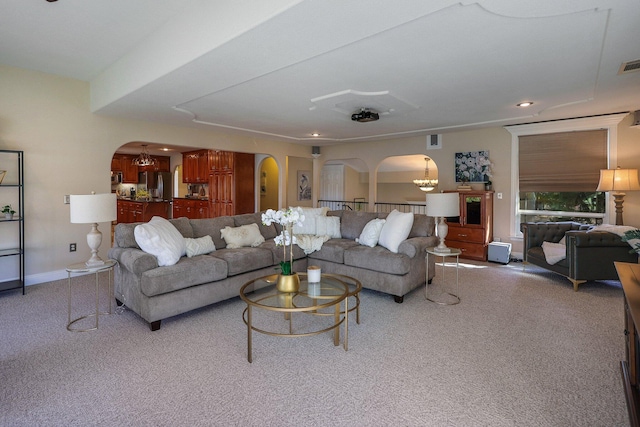 carpeted living room featuring an inviting chandelier