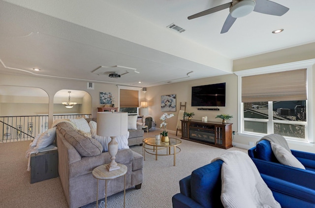 living room featuring ceiling fan with notable chandelier and light colored carpet