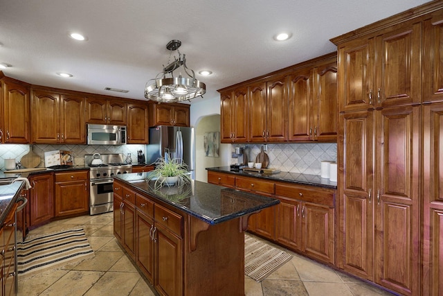 kitchen featuring hanging light fixtures, backsplash, a kitchen island, stainless steel appliances, and a chandelier