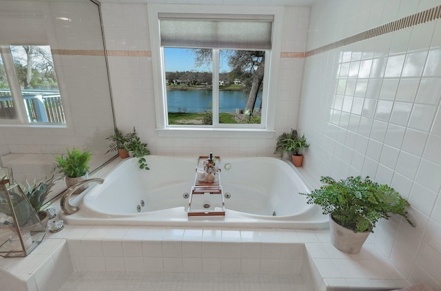 bathroom with tiled tub, plenty of natural light, and a water view