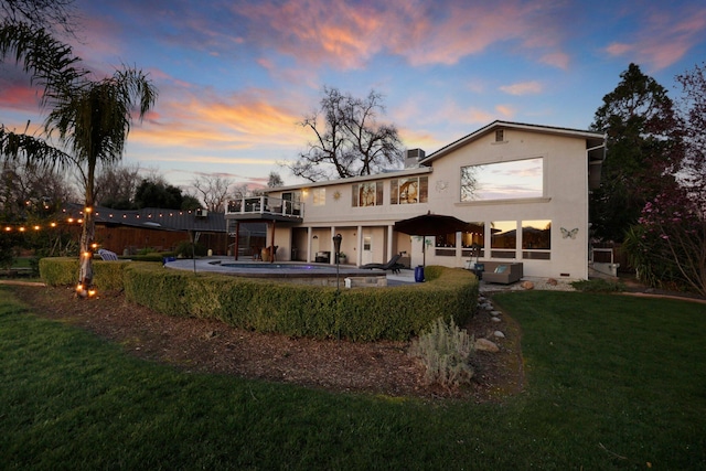 back house at dusk with a lawn and a patio area