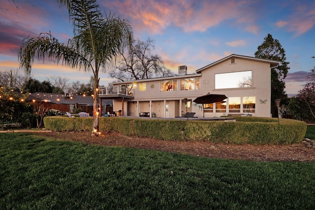 back house at dusk with a lawn