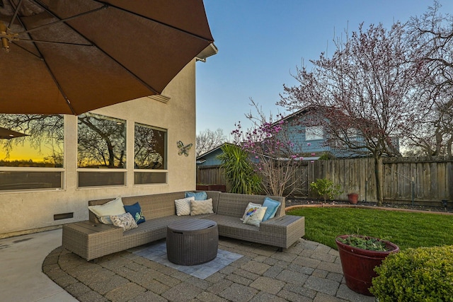 patio terrace at dusk featuring outdoor lounge area and a yard