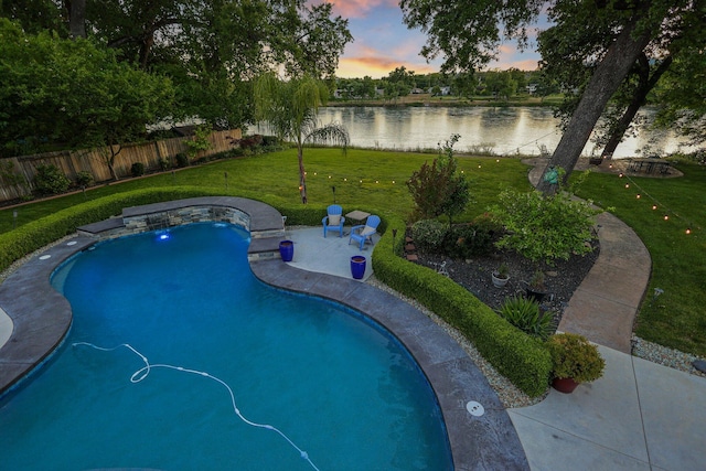 pool at dusk with a lawn and a water view