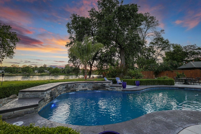 pool at dusk featuring pool water feature and a patio area