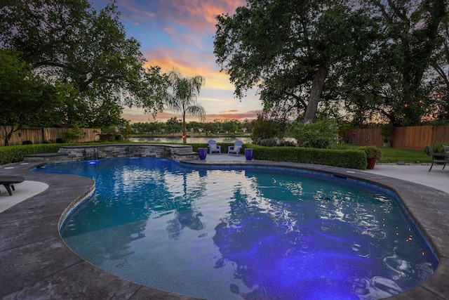 pool at dusk with a patio area