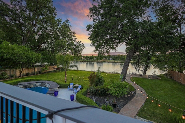 yard at dusk with a patio and a water view