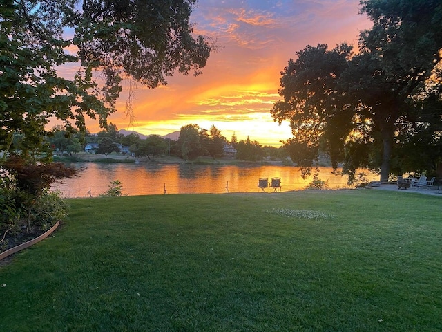 yard at dusk featuring a water view