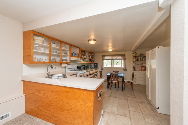 kitchen with white appliances, kitchen peninsula, and sink