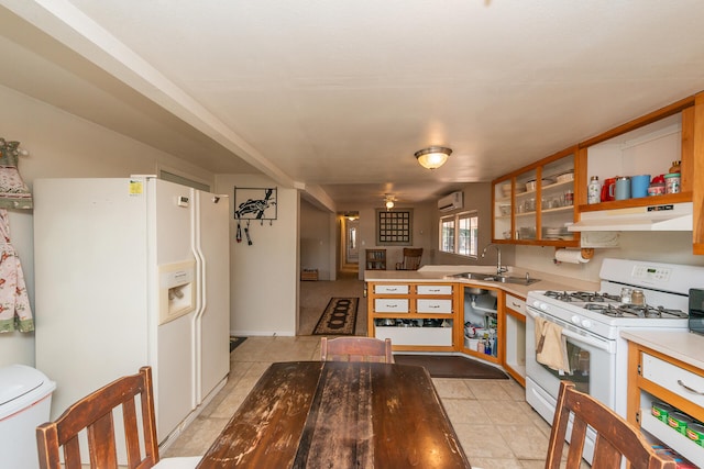 kitchen with white appliances, kitchen peninsula, light tile patterned floors, sink, and a wall mounted AC