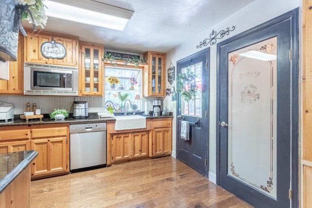 kitchen with dark stone counters, light hardwood / wood-style floors, sink, and stainless steel appliances