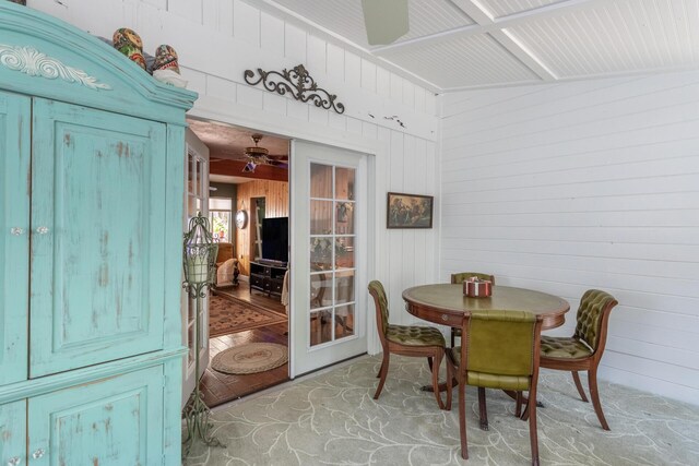 dining room with wooden walls, vaulted ceiling, and light hardwood / wood-style flooring