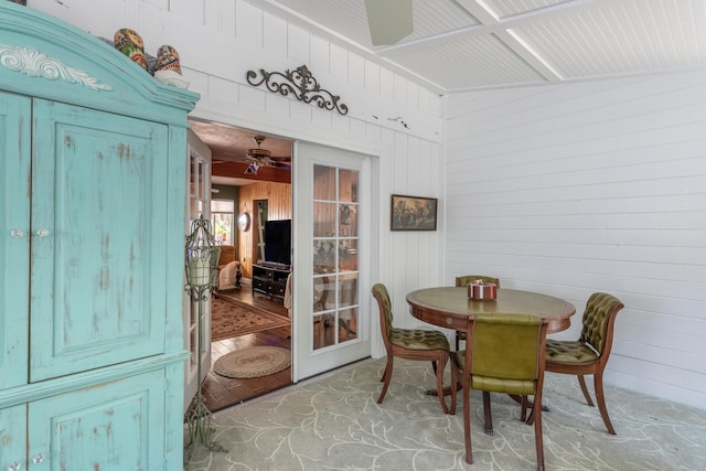 dining space with a ceiling fan and wooden walls